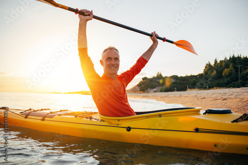 Smiling senior kayaker enjoy kayaking on sunset sea