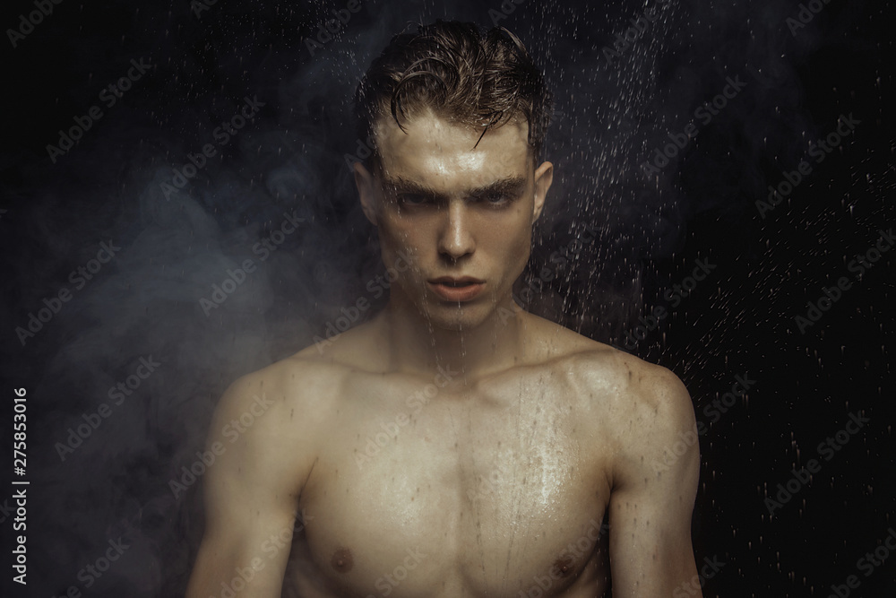 Handsome wet sport sexy stripped guy portrait with waterdrops and smoke on isolated black background Handsome wet sport sexy stripped guy portrait with waterdrops and smoke on isolated black background