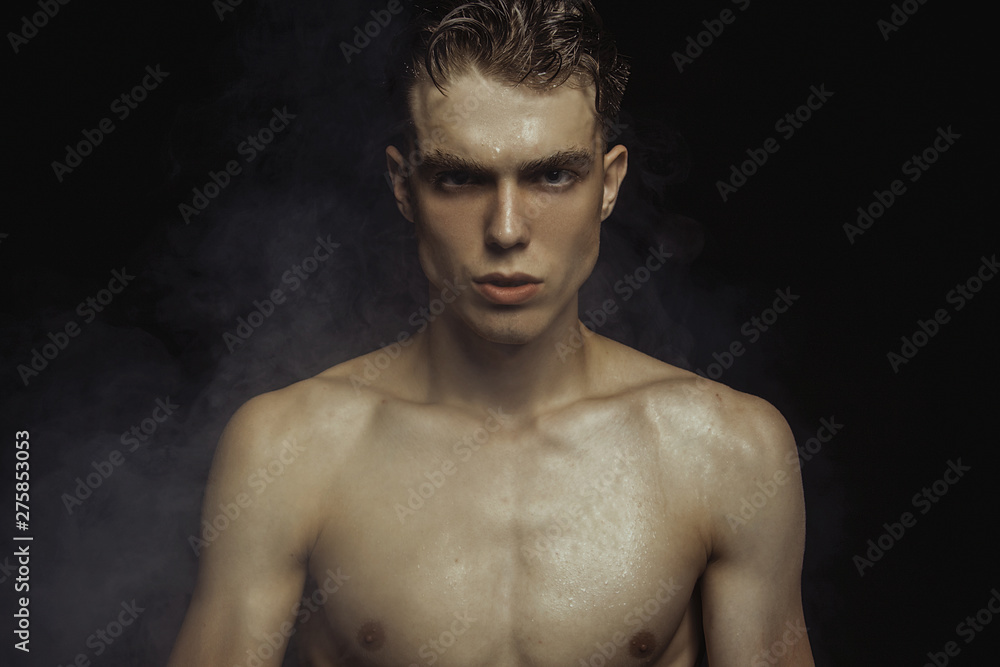 Handsome wet sport sexy stripped guy portrait with waterdrops and smoke on isolated black background Handsome wet sport sexy stripped guy portrait with waterdrops and smoke on isolated black background