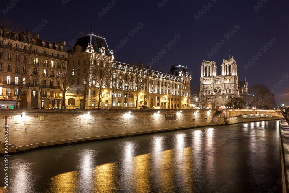 Notre Dame Cathedral and the Seine river in Paris at night, France.