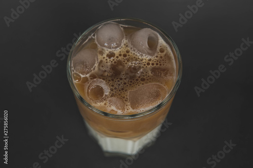 large transparent glass filled with cold summer drink coffee with milk photographed on the isolated gray background picture for the menu.
