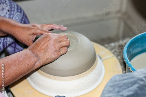 hands of a potter, creating an bowl on the circle, Pottery polishing process with 2 hands in the final step. Before entering the kiln.