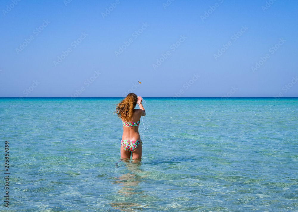 Slim and athletic girl in a colourful bikini having fun on a wonderful beach with crystal clear water -vacation-fitness-wellness