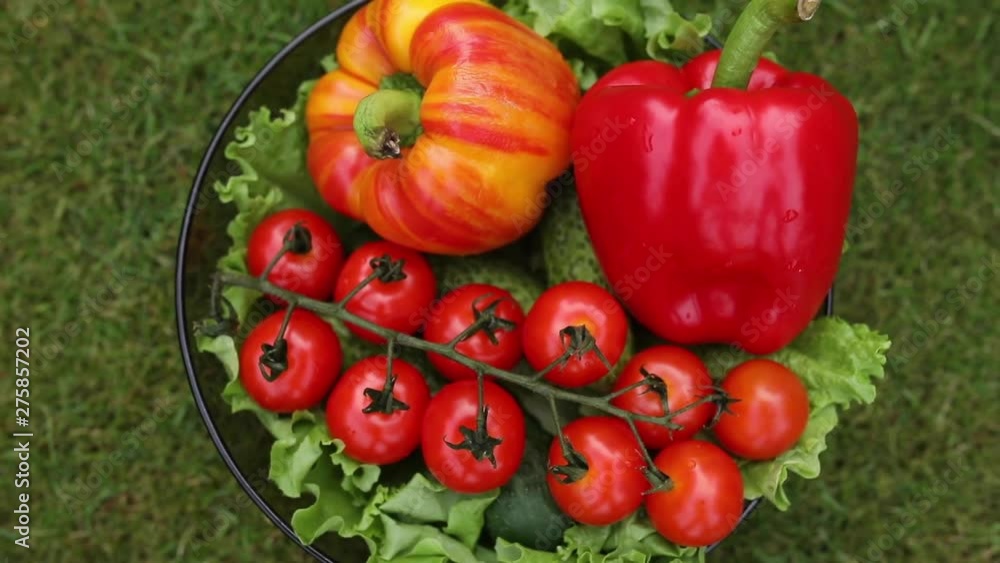Top view stock video of fresh green and red vegetables in the bowl on green lawn. Top view stock video of fresh green and red vegetables in the bowl on green lawn.