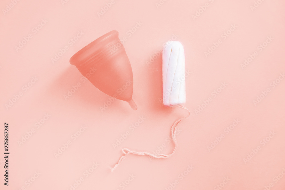 Reusable menstrual cup and tampon toned with main trendy Living Coral color of the year 2019, Concept female intimate hygiene period products and zero waste. Flat lay, top view. copyspace