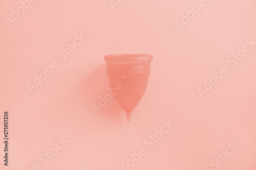 Reusable menstrual cup toned with main trendy Living Coral color of the year 2019, Concept female intimate hygiene period products and zero waste. Flat lay, top view. copyspace photo