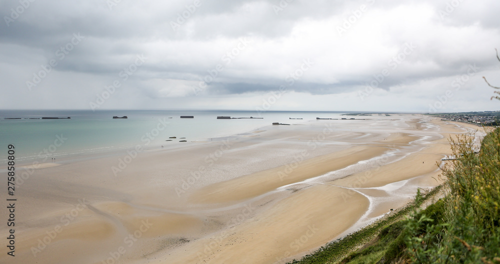 Low tide at the beaches of Arromanches, Normandy, a dark day with clouds remembering the soldiers who died storming the beach. 