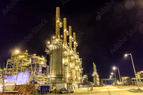 Photo of metal structures on the large oil and gas processing plant. Night photo of pipes and metal constructions at an oil or gas field plant. Construction of an oil refinery.