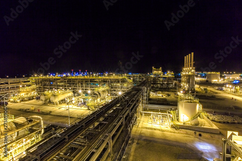 Photo of metal structures on the large oil and gas processing plant. Night photo of pipes and metal constructions at an oil or gas field plant. Construction of an oil refinery.