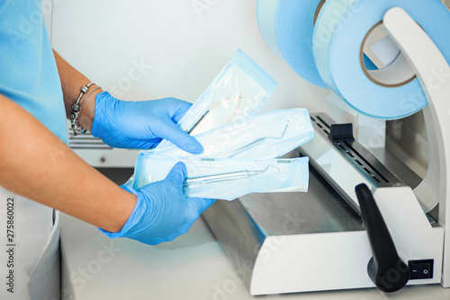 Obraz na płótnie Dentist assistant's hands holding packaged with vacuum packing machine medical instruments ready for sterilizing in autoclave