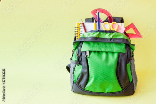 Composition with backpack and school stationery on yellow background