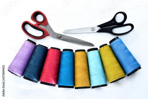 Colorful sewing thread reels on white background with scissors