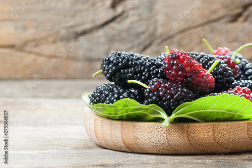 Quadro em tela Fresh ripe black mulberry berry fruit with leaf on rustic wooden background, bla