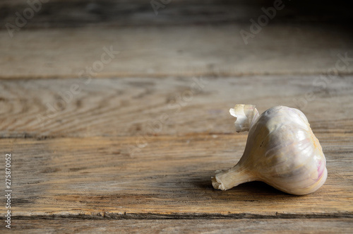 A whole head of garlic on the background of old boards.