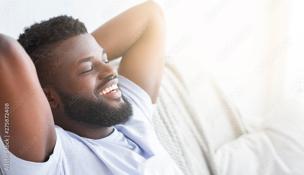 Satisfied black guy relaxing at home, lying with closed eyes Satisfied black guy relaxing at home, lying with closed eyes