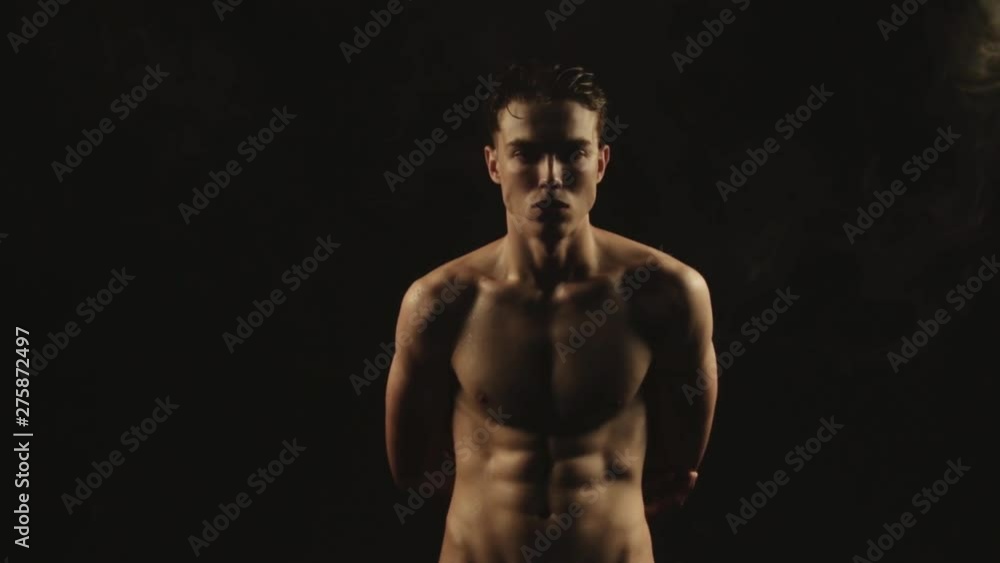 Sexy sport stripped guy in water drops with smoke on isolated black background Sexy sport stripped guy in water drops with smoke on isolated black background