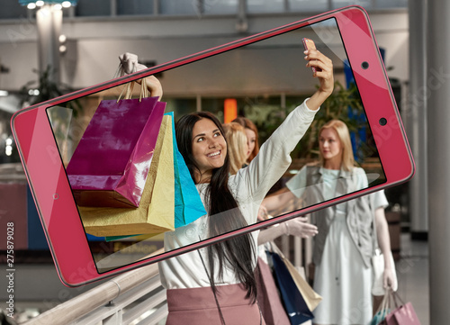 Photo of happy pretty woman with shopping bags on smartphone's screen