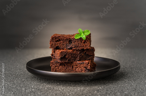 Dark chocolate and cocoa brownie fudge cakes dessert with mint against black and grey stone background