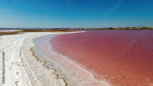 The red-colored salt lagoon of the Spanish city of Torrevieja. The white salt looks like snow. There are footprints to see. photo