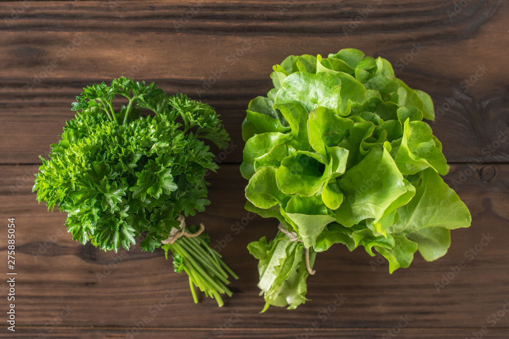 Parsley and lettuce leaves in bunches on the table. Flat lay. Parsley and lettuce leaves in bunches on the table. Flat lay.