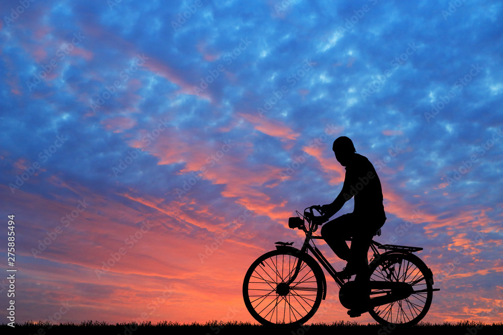 Fototapeta premium Silhouette man and bike relaxing on blurry sunrise sky background.
