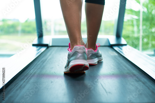 womans muscular legs on treadmill in the gym, closeup. © Denis
