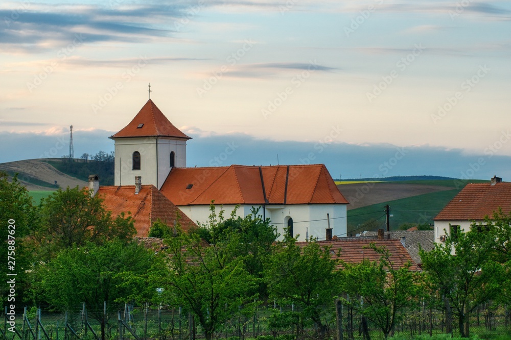 Obraz premium Moravian spring landscape of the village of Zeletice with fields, orchards and gardens, brick church of St. James, tiled houses