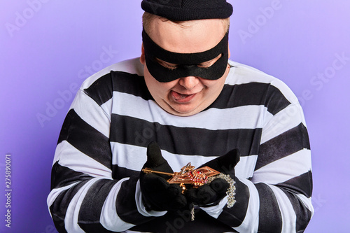 excited happy thief looking at stolen ornament. close up photo. isolated blue background. studio shot. photo