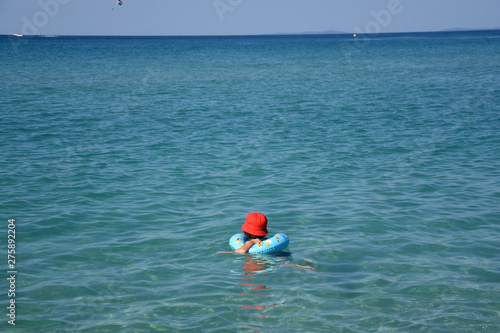 Little boy with inflatable ring swimming in the sea. Child with a floating ring enjoy in water