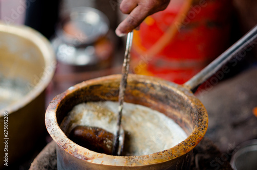 Tea boiling in a dirty open saucepan on a roadside stall in indian city