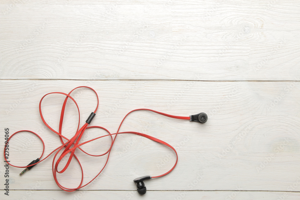 Small red-black headphones for a smartphone on a white wooden background. top view Small red-black headphones for a smartphone on a white wooden background. top view
