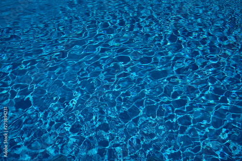 Swimming pool water surface with sparkling light reflections. Clear blue water from a swimming pool with very nice reflections.