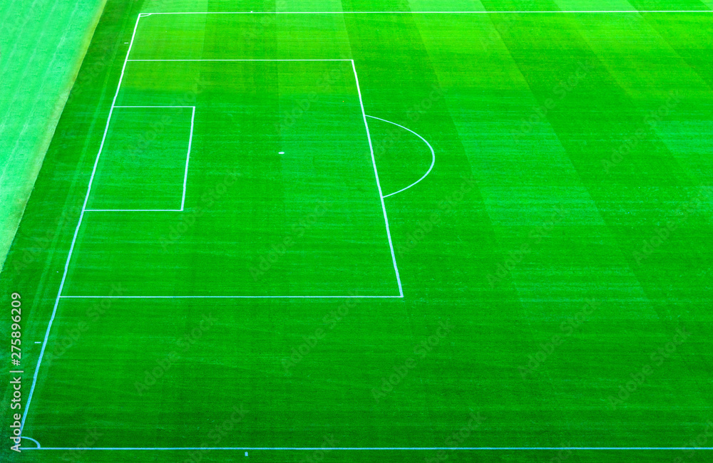Top aerial view of football pitch soccer field with green grass lawn, pattern texture, white marking stripes at sports stadium