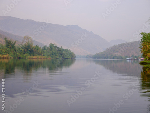  The river that flows from Srinagarindra Dam, Kanchanaburi, Thailand has a mountain as a backdrop.
