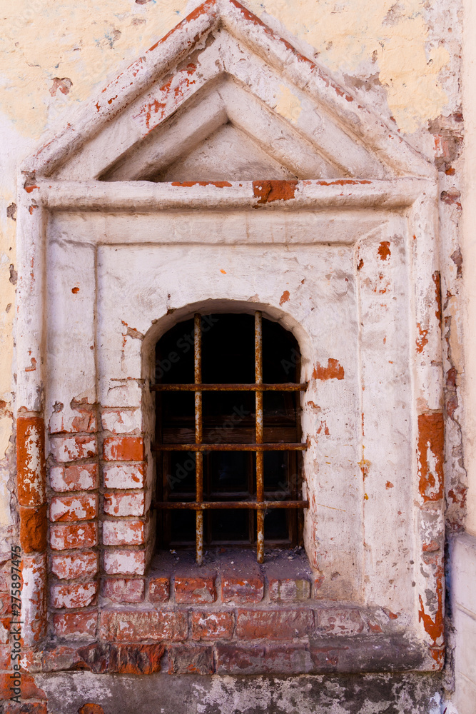 Fototapeta premium old destructed window surround made of bricks. instead of a window there is a lattice
