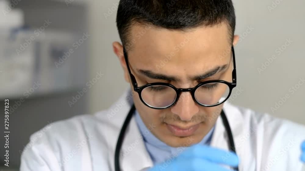 Close up of male middle eastern doctor preparing syringe with vaccine for terrier dog at vet clinic