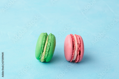 Pistachio and crimson macaroons on a light blue background. Close-up.