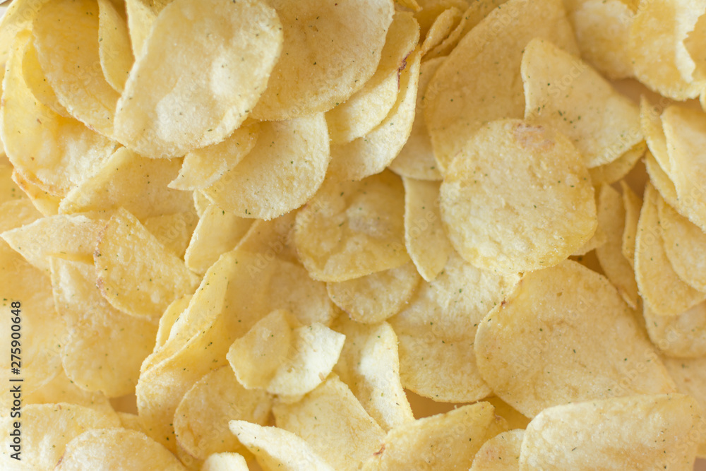 Heap of potato crisps on wooden background. Potato chips, unhealthy eatting.