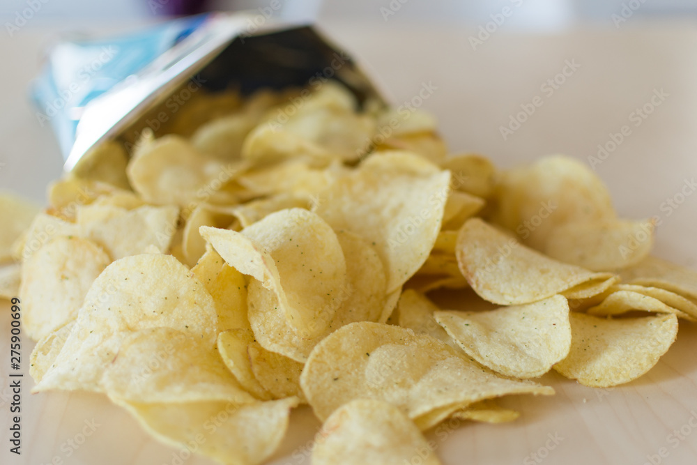 Heap of potato crisps on wooden background. Potato chips, unhealthy eatting. Heap of potato crisps on wooden background. Potato chips, unhealthy eatting.