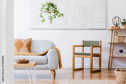 The stylish boho compostion at living room interior with design gray sofa, grenn armchair, wooden coffee table, bamboo shelf and elegant personal accessories. Honey yellow pillow and plaid. Home decor photo