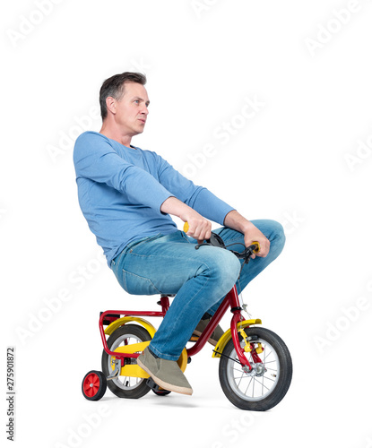Happy man in jeans and t-shirt on a children's bike, isolated on white background.