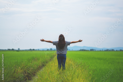 A woman standing and stretching arms in a beautiful rice field with feeling relaxed and fresh