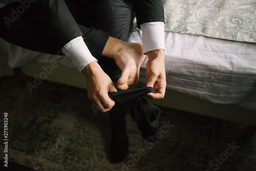 Man putting socks on his feet close-up in bedroom