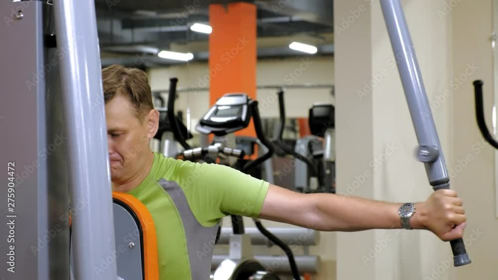 Man does a butterfly exercise on the simulator in a fitness studio.healthy lifestyle. Fitness and Sport Man does a butterfly exercise on the simulator in a fitness studio.healthy lifestyle. Fitness and Sport