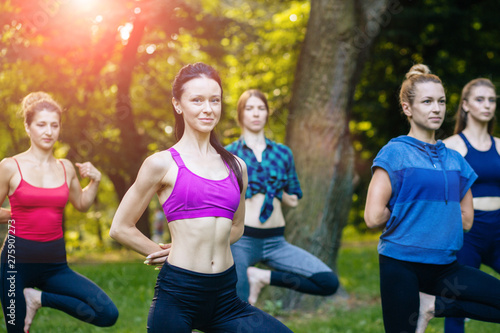 Fototapeta Naklejka Na Ścianę i Meble -  Yoga or pilates at park, group of mixed age women doing different pose while standing in morning time. Teamwork, sport, good mood and healthy life concept. Seria photo with real people models.