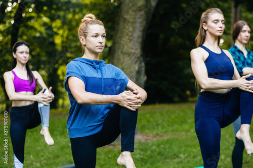 Yoga or pilates at park, group of mixed age women doing different pose while standing in morning time. Teamwork, sport, good mood and healthy life concept. Seria photo with real people models.