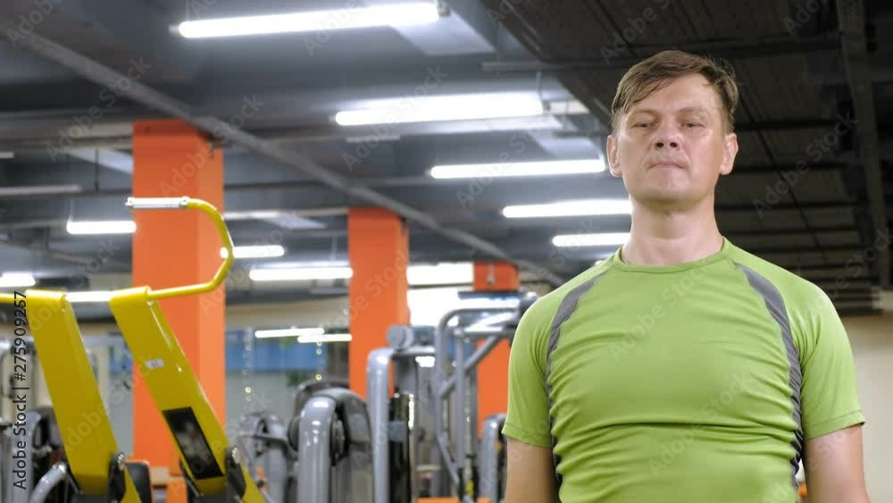 A man doing an exercise on the back delta with dumbbells sitting with a straight grip in a fitness studio A man doing an exercise on the back delta with dumbbells sitting with a straight grip in a fitness studio
