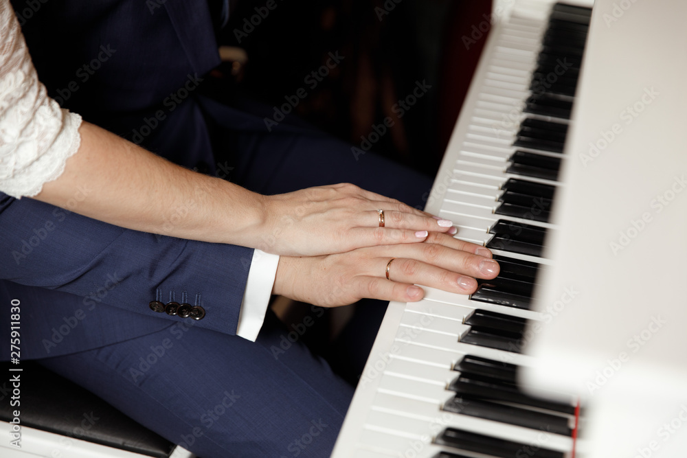 Obraz premium Groom and and bride hands with rings. On piano, close up