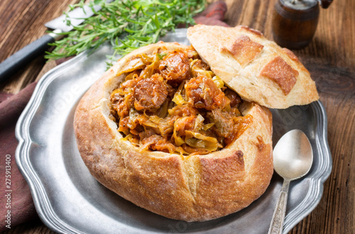 Traditional Polish kraut stew bigos with sausage and meat filled in white bread as closeup on a pewter plate photo
