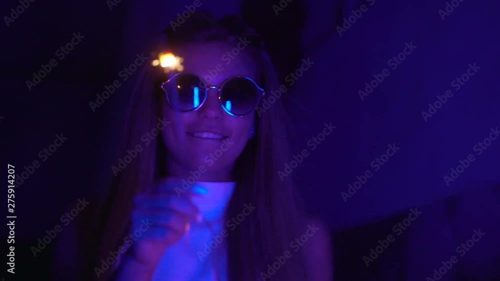 Young pretty girl near glowing neon lights of the city at night. Hipster teenager in glasses and beautiful lenses Young pretty girl near glowing neon lights of the city at night. Hipster teenager in glasses and beautiful lenses